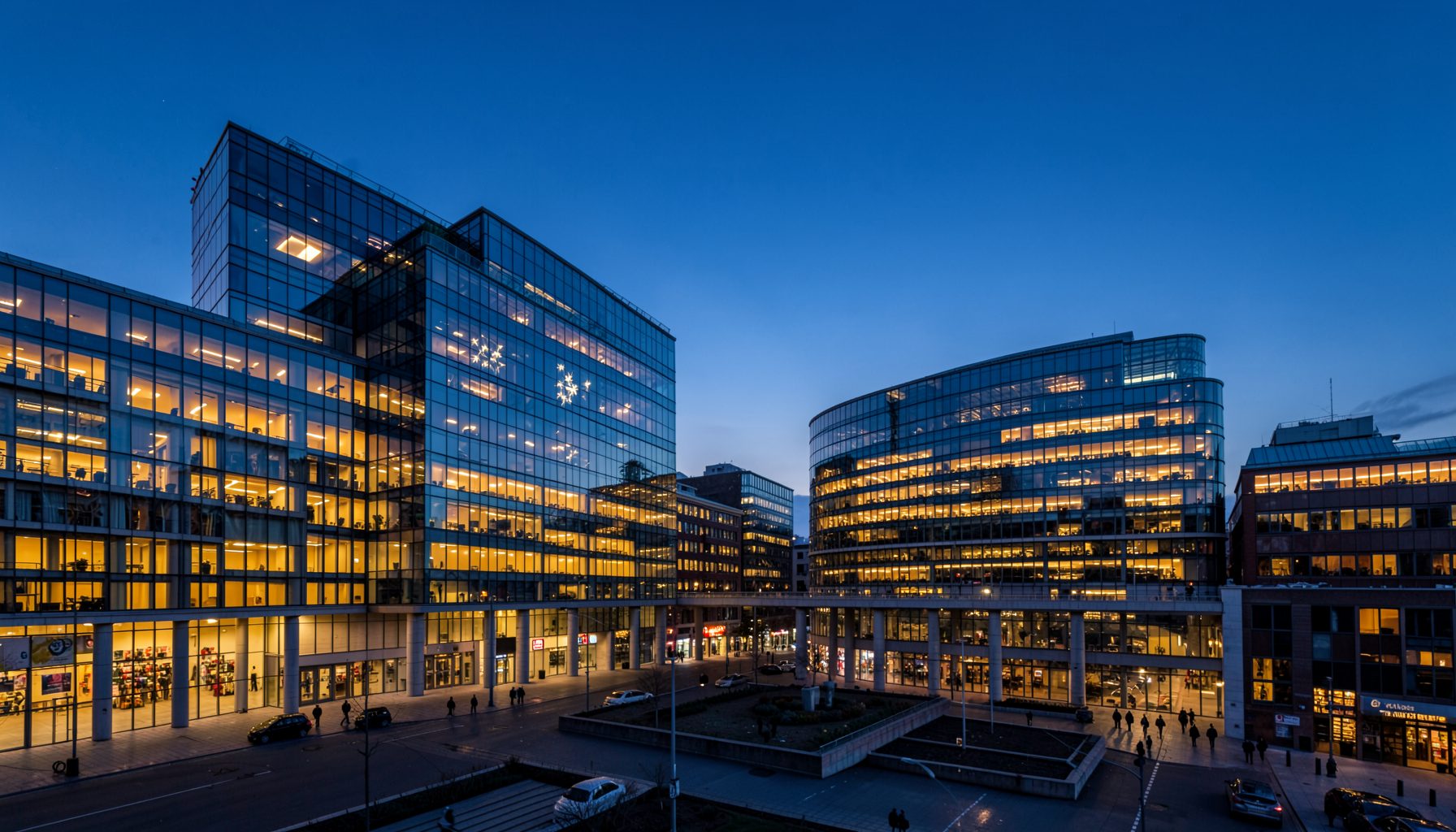 A panoramic view of the European quarter in Brussels at dusk, with the glass facades of EU institution buildings glowing in warm amber light